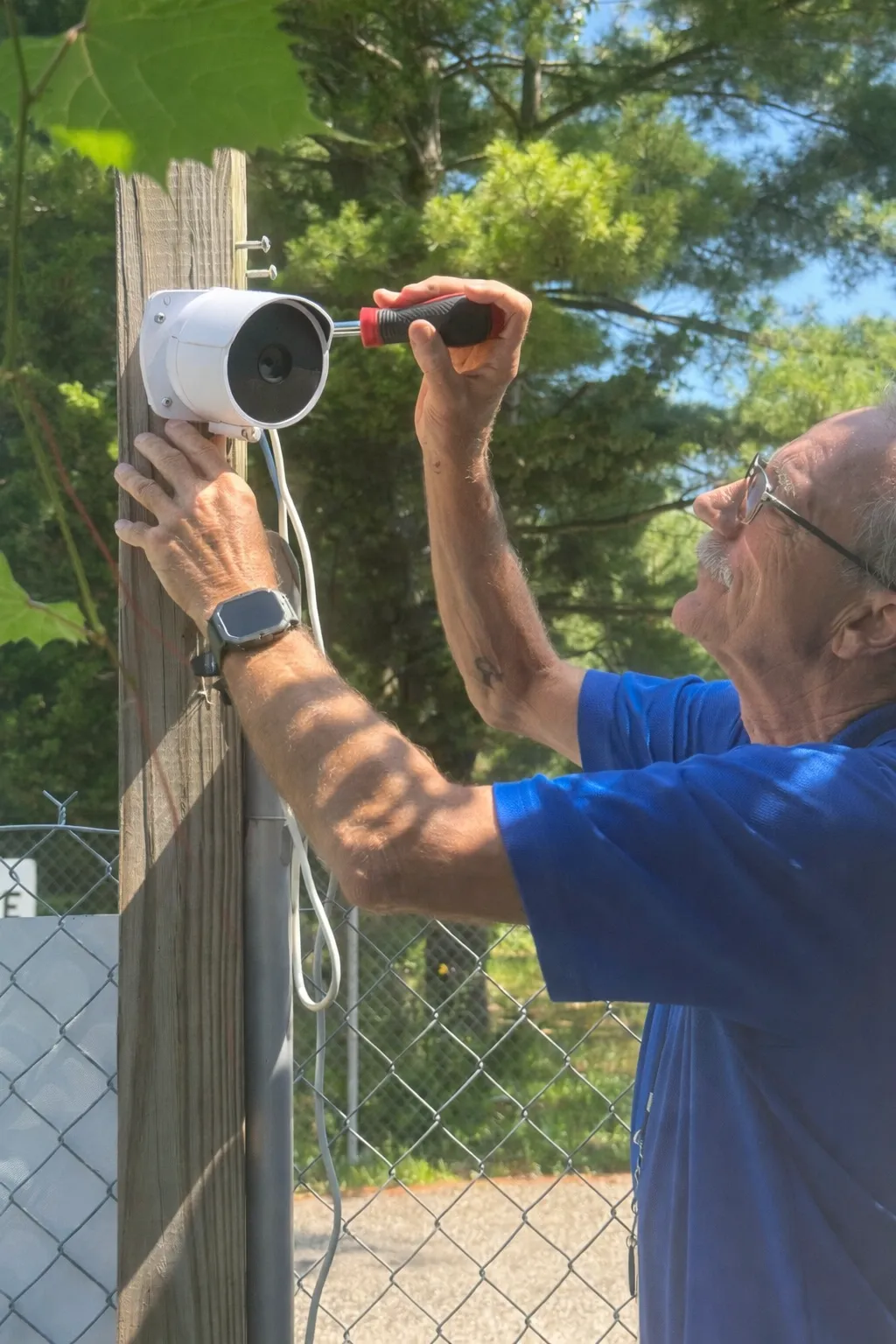 Technician installing a security camera on a fence post