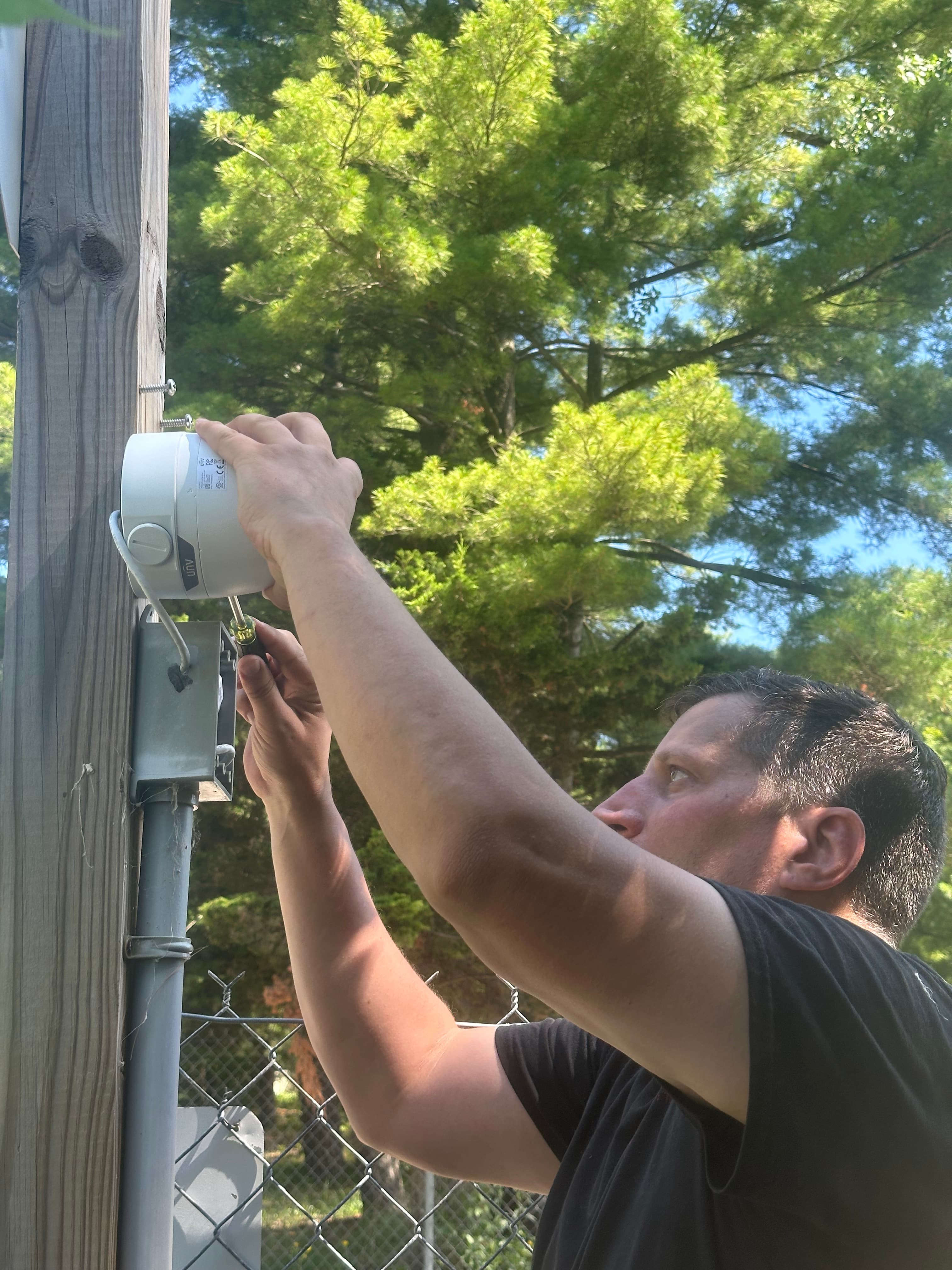 Security technician installing camera on pole